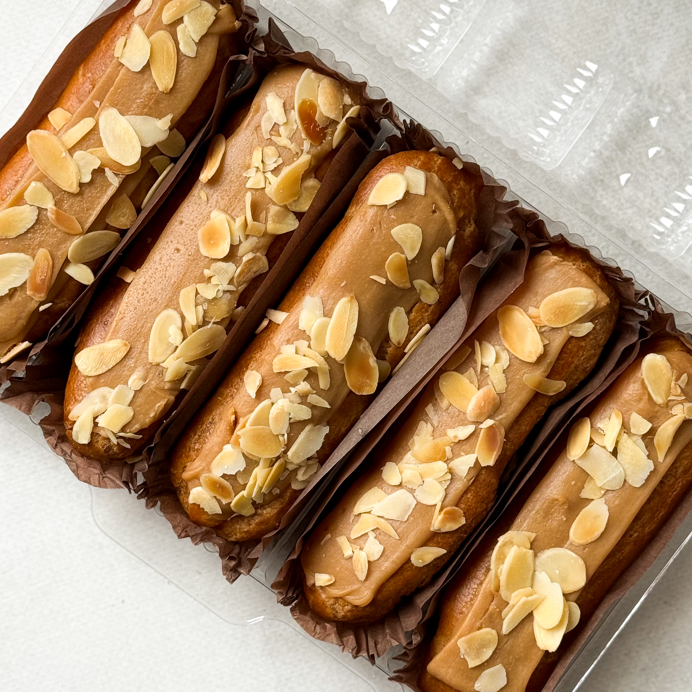 Карамельный эклер с кремом из взбитых сливок с карамелью, украшенный лепестками миндаля изображение 3