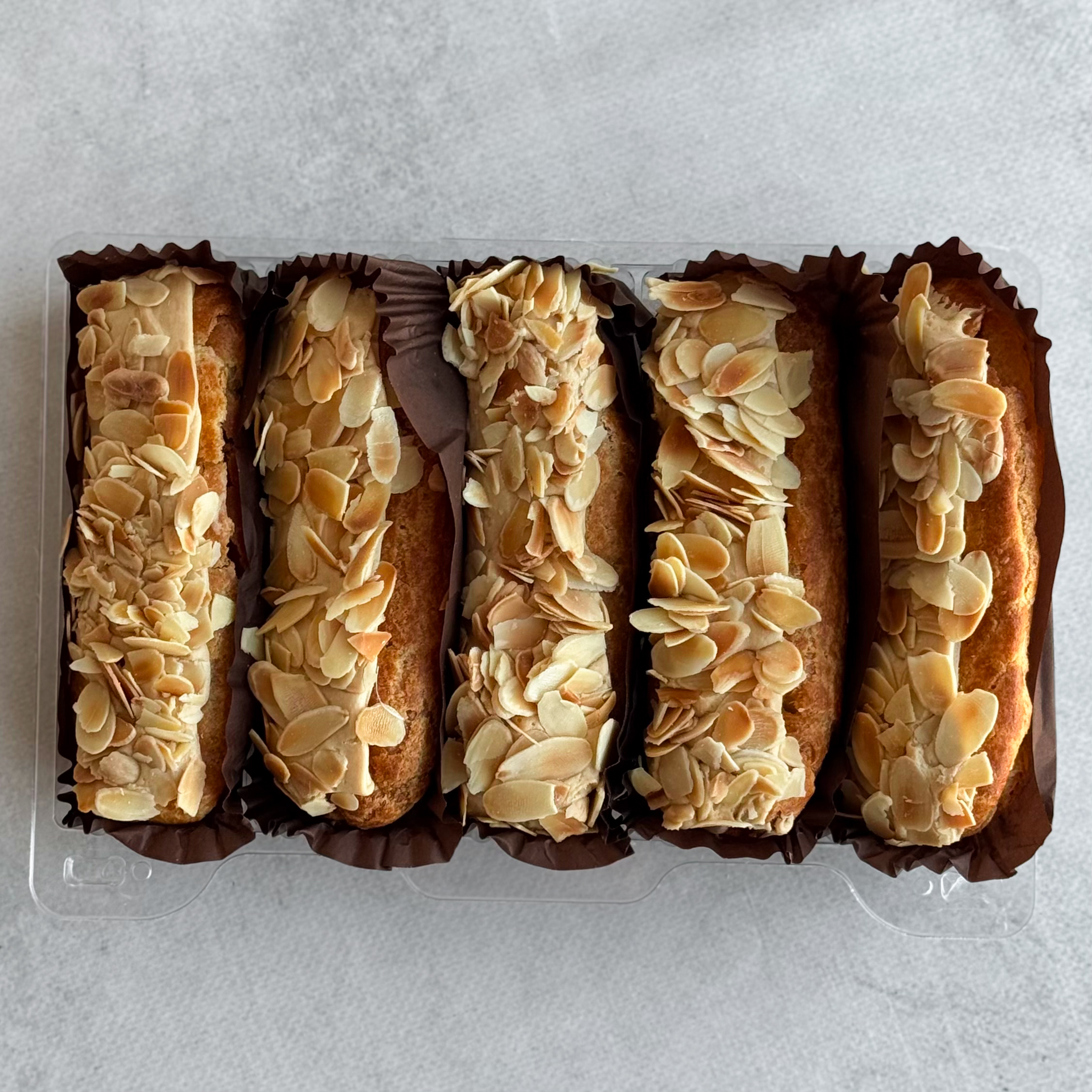 Карамельный эклер с кремом из взбитых сливок с карамелью, украшенный лепестками миндаля изображение 3