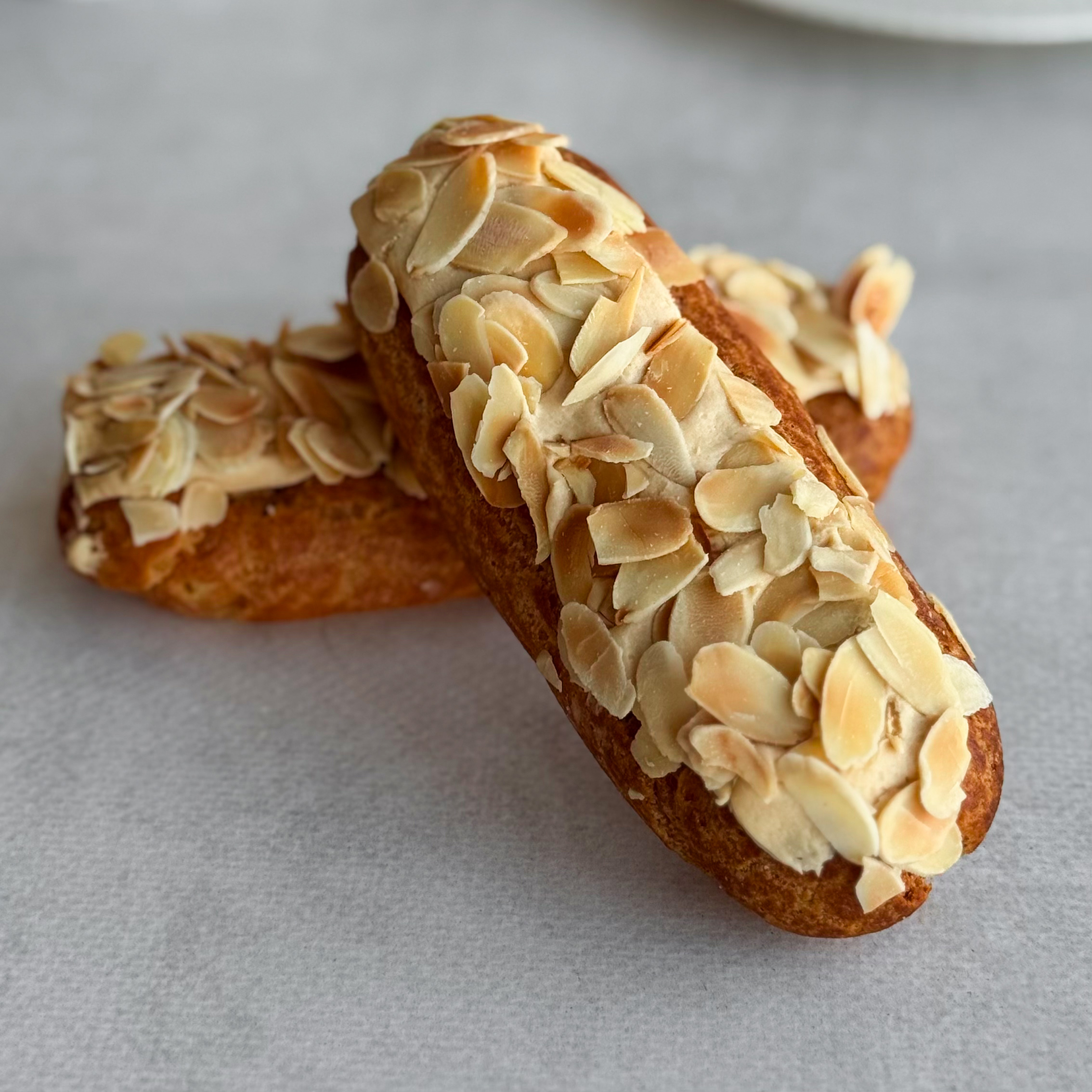 Карамельный эклер с кремом из взбитых сливок с карамелью, украшенный лепестками миндаля изображение 4