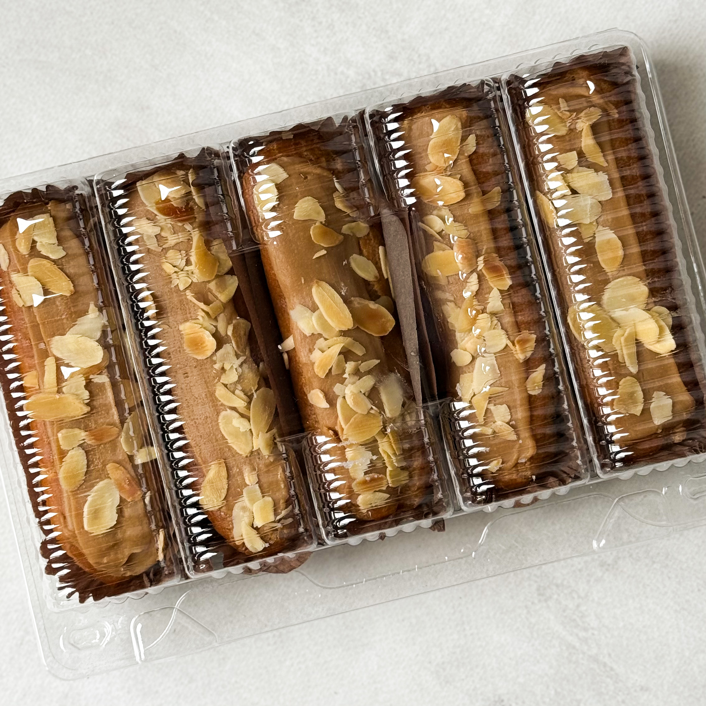 Карамельный эклер с кремом из взбитых сливок с карамелью, украшенный лепестками миндаля изображение 6