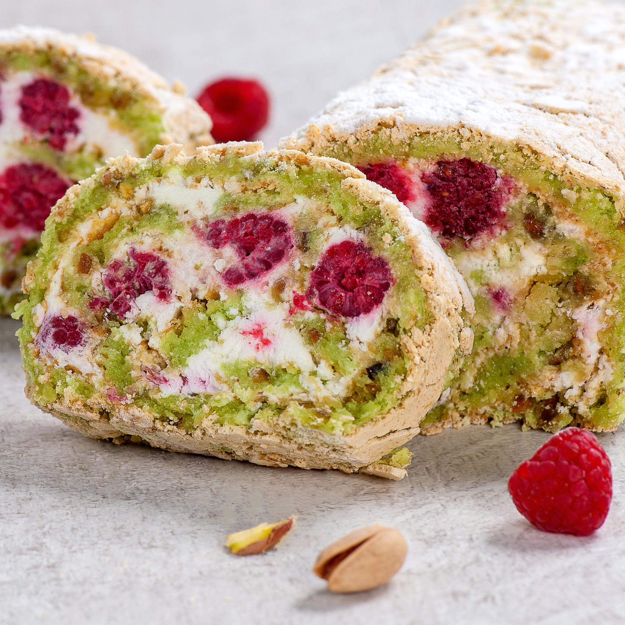 Внутри фисташкового бисквита нежный крем на основе взбитых сливок и спелая малина. Невероятно сочный вкус! Рулет украшен посыпкой из сахарной пудры. изображение 1