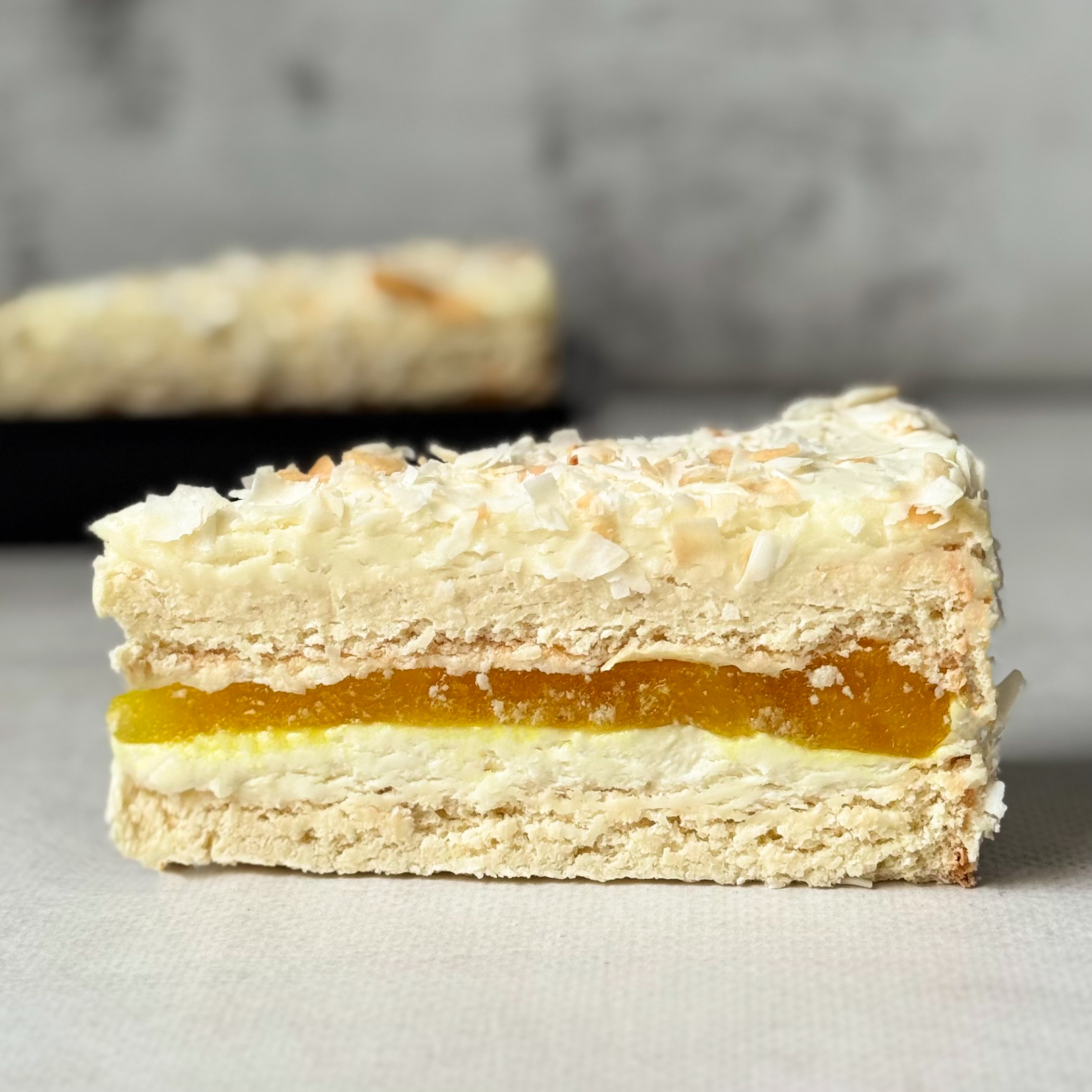 Изысканный торт из слоев кокосового бисквита, крема на основе белого шоколада, взбитых сливок и сочного слоя ананасового конфитюра с кусочками ананаса. Сверху торт украшен обжаренным кокосовым кранчем. изображение 2