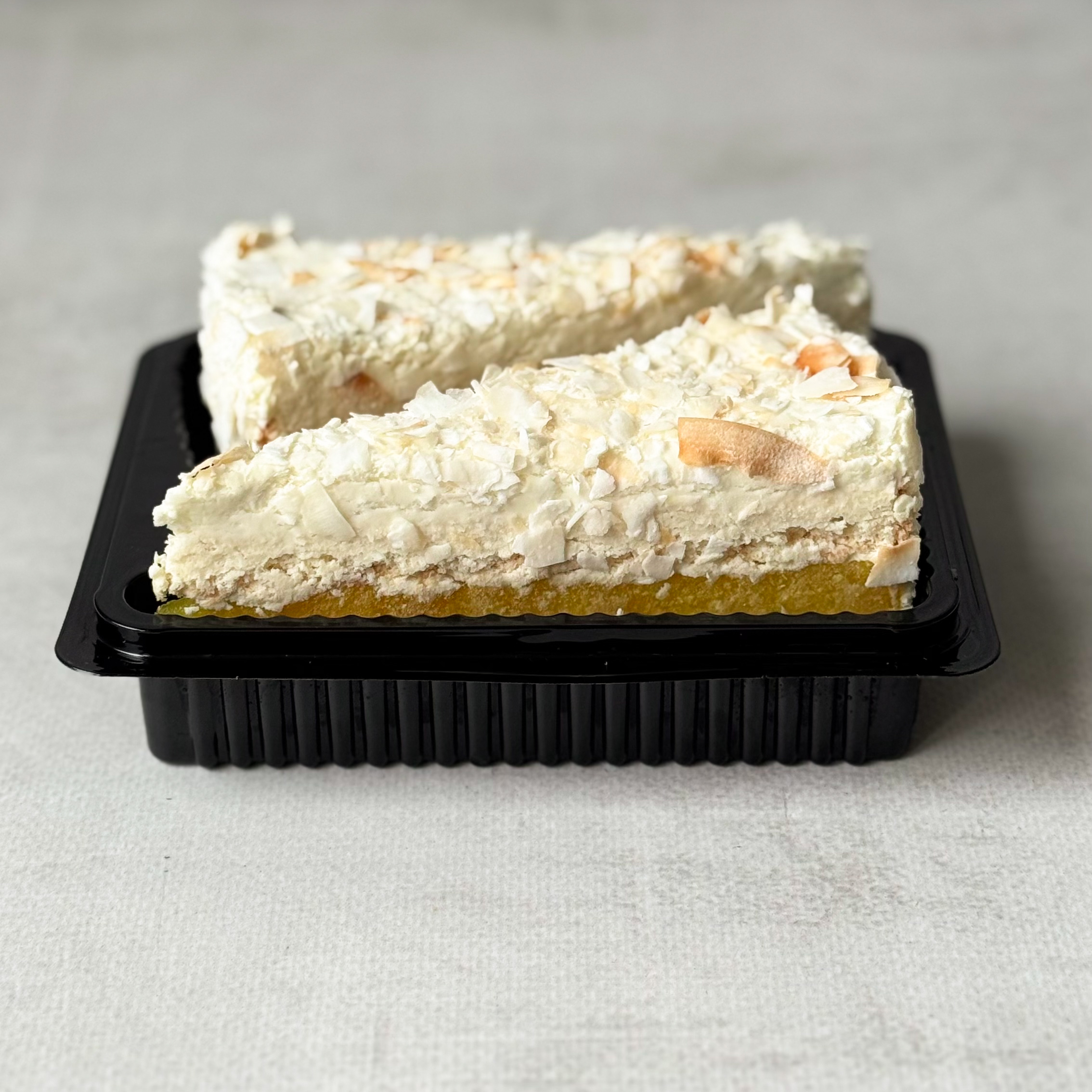 Изысканный торт из слоев кокосового бисквита, крема на основе белого шоколада, взбитых сливок и сочного слоя ананасового конфитюра с кусочками ананаса. Сверху торт украшен обжаренным кокосовым кранчем. изображение 4