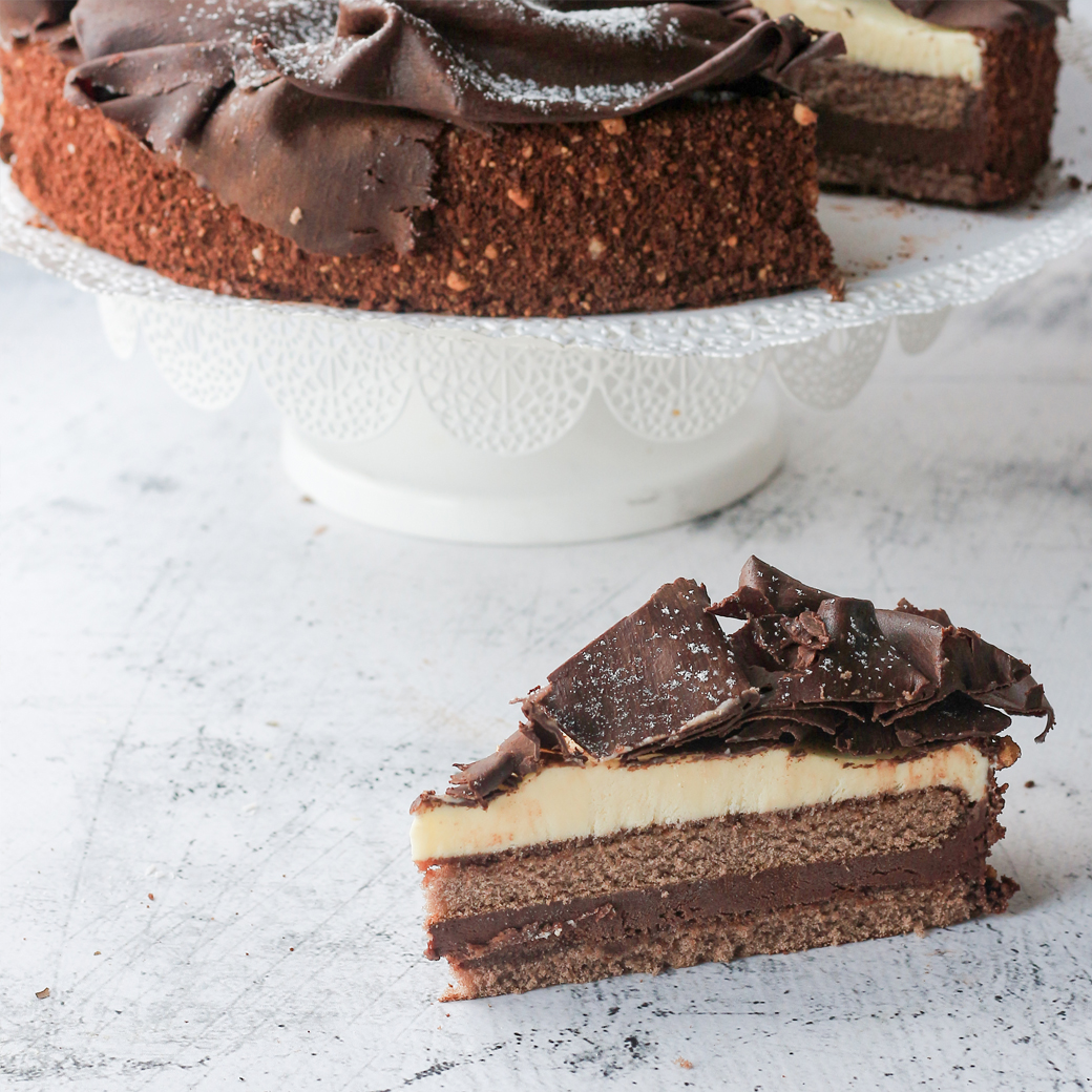 Шоколадный бисквит с заварным шоколадно-ореховым кремом украшенный темным шоколадом. Торт не нарезан. изображение 2